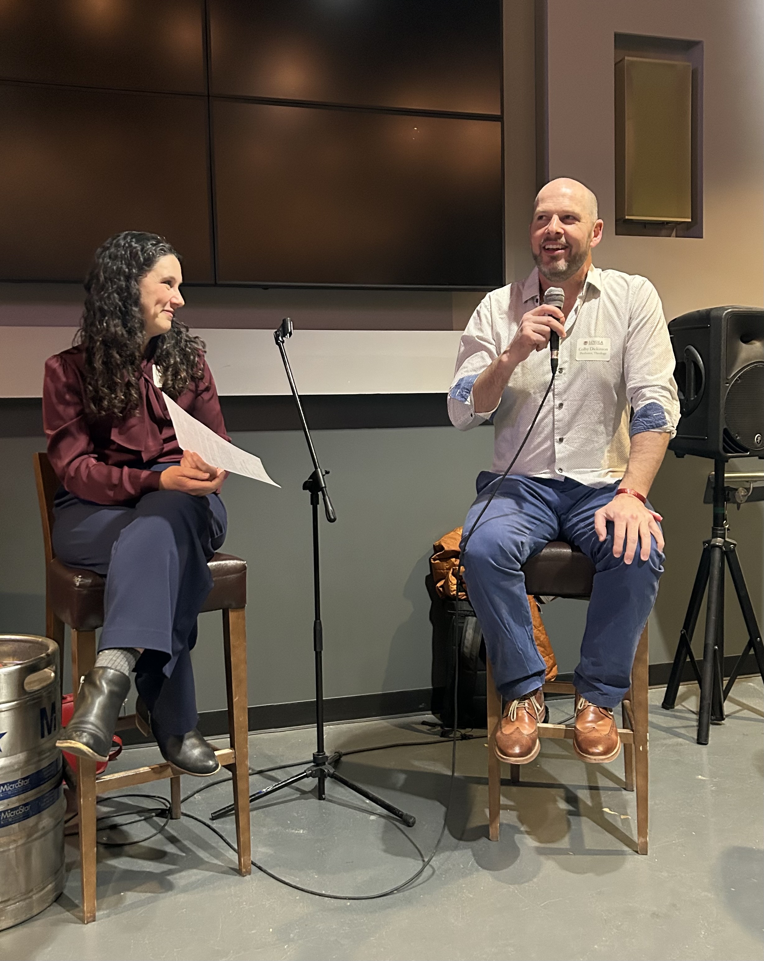 two people sitting speaking with a microphone