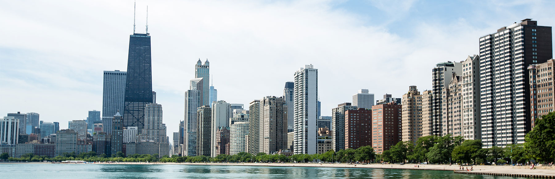 Chicago Skyline from a northern vantage point. The sky is clear and the lake is still.