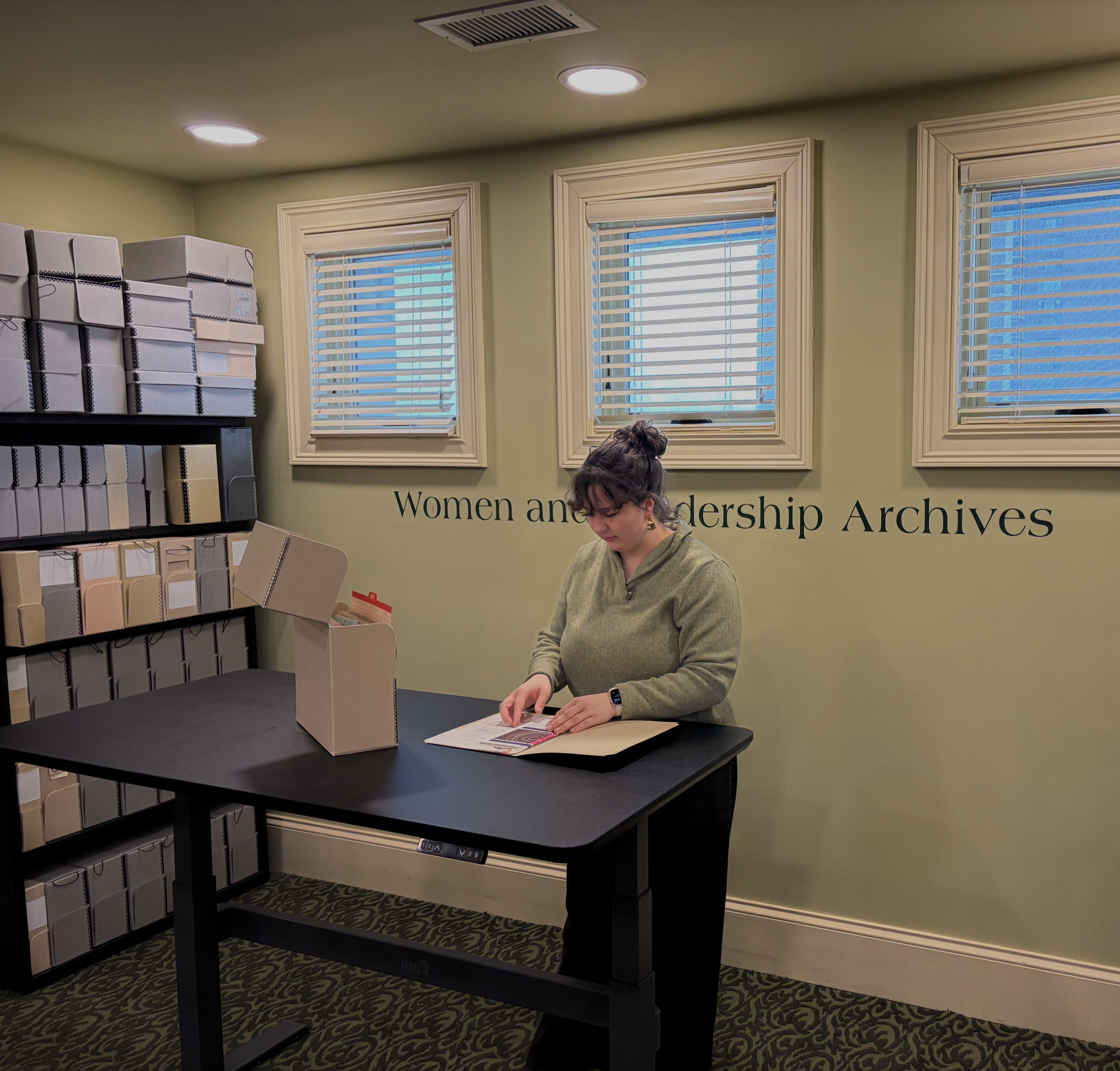 Researcher at the standing desk in the WLA reading room looking at materials in a folder