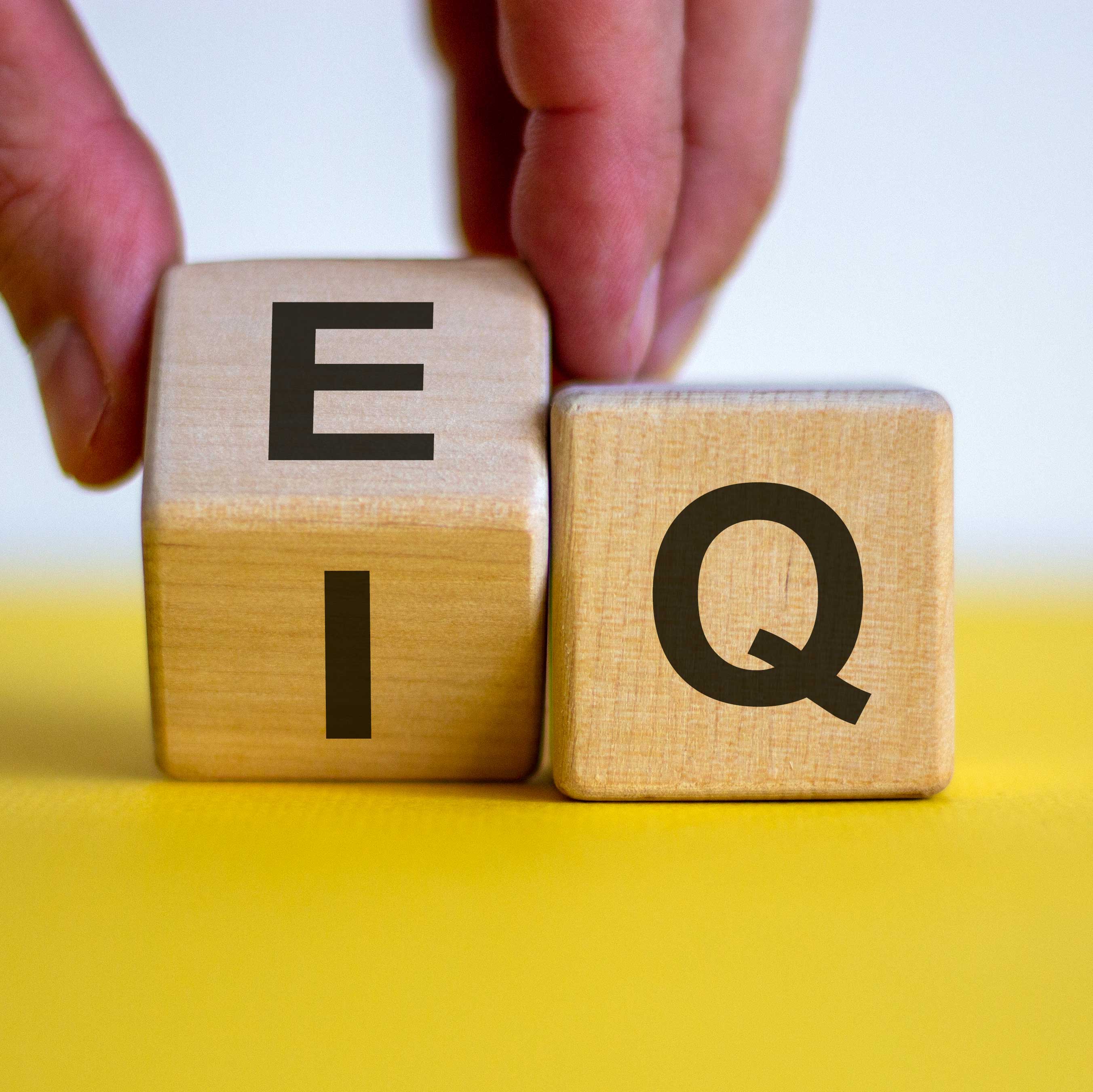 Two wooden squares with letters on them and a hand turning the first one over