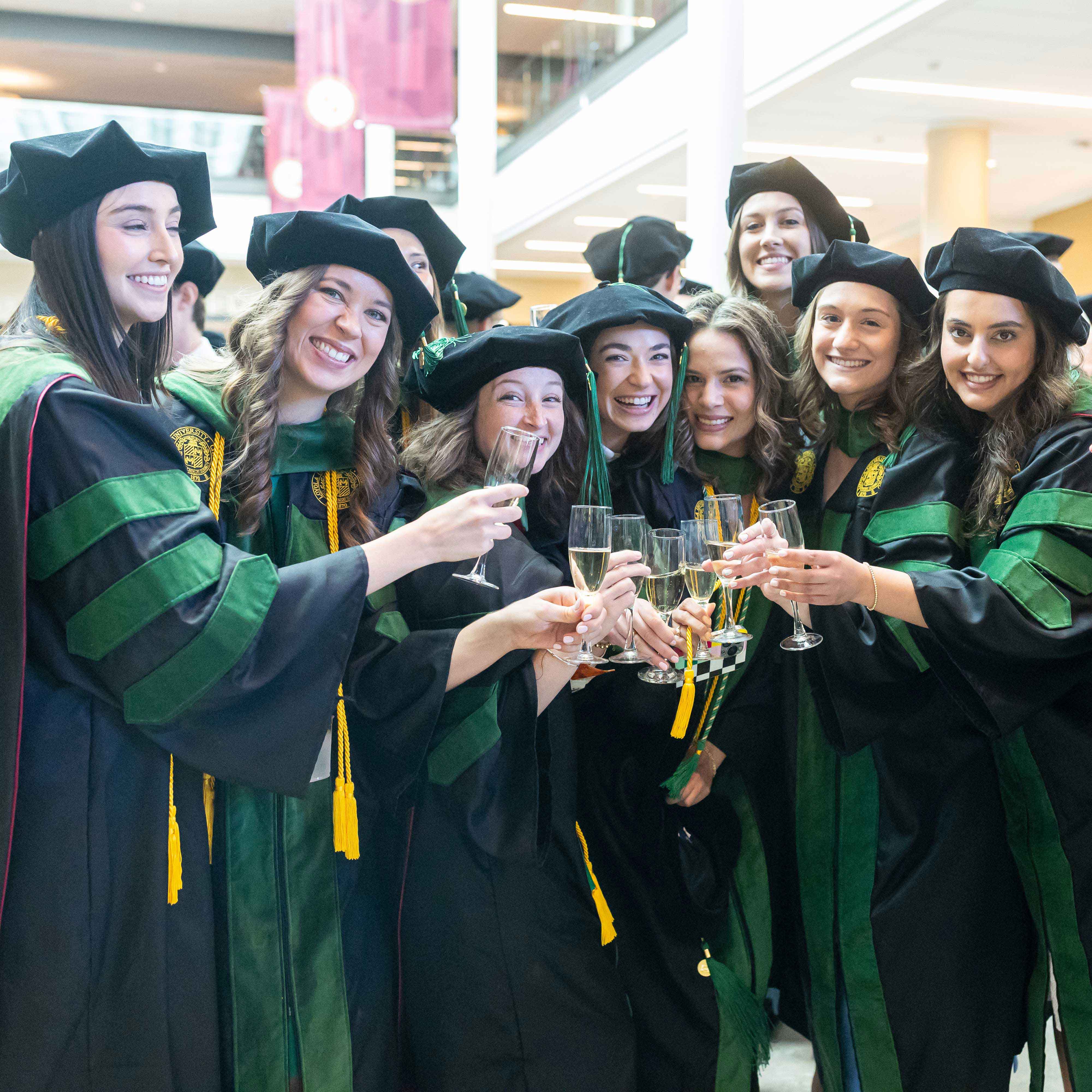 Group of students wearing caps and gowns and toasting with champagne glasses